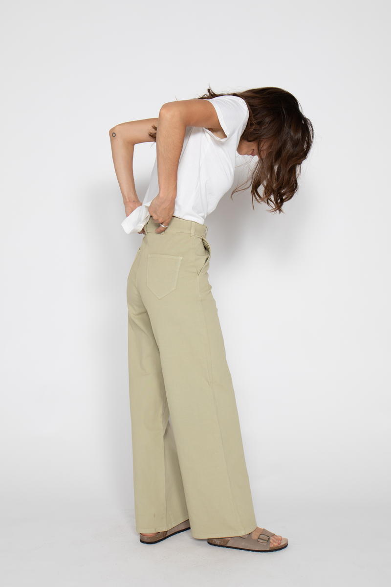 Close-up of lightweight high-waisted flare pants, highlighting waistband and pockets, paired with sandals.
