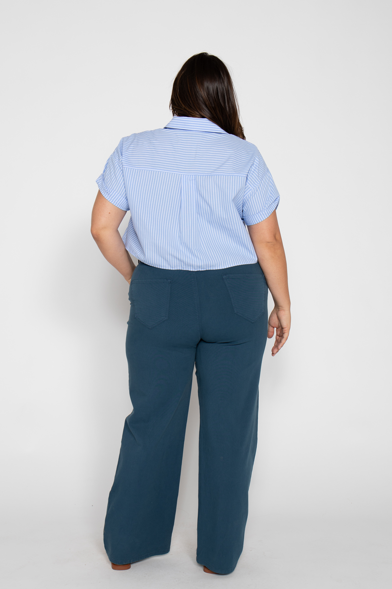 Back view of plus-size model in blue wide-leg pants with a casual button-down shirt, showing a relaxed fit.