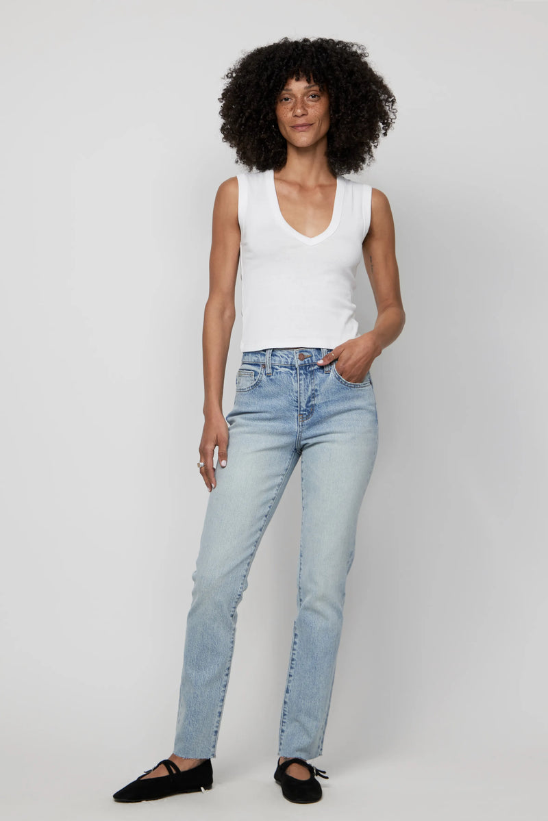 Woman wearing high-rise relaxed fit light wash jeans and a white tank top, front-facing view.
