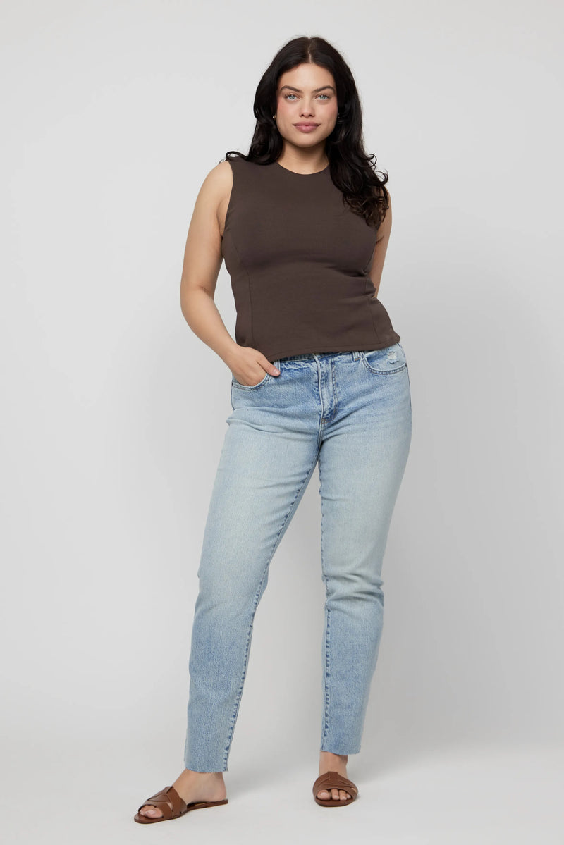 Plus-size woman wearing high-rise relaxed fit jeans in light wash denim, styled with a brown tank.