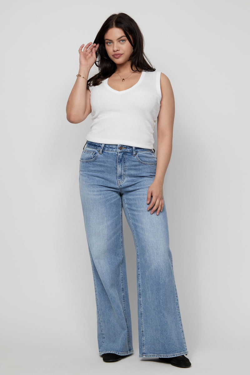 Woman modeling high-rise wide-leg jeans in a relaxed pose, styled with a fitted white tank top.
Video of model wearing high-rise wide-leg jeans, walking to highlight drape and soft stretch fit.