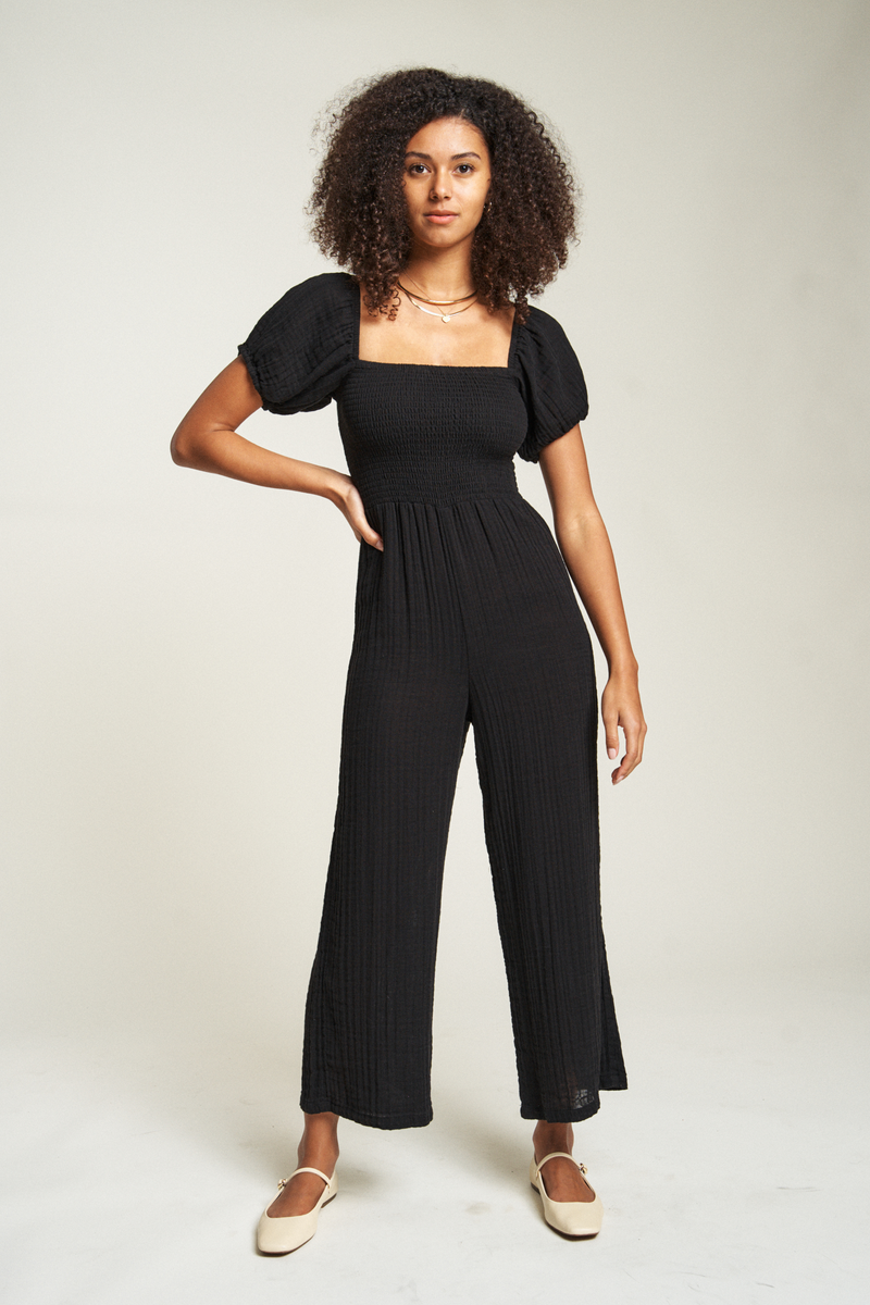 Black cotton romper with a relaxed fit, square neckline, and flowy silhouette, perfect for a stylish, easygoing summer look.