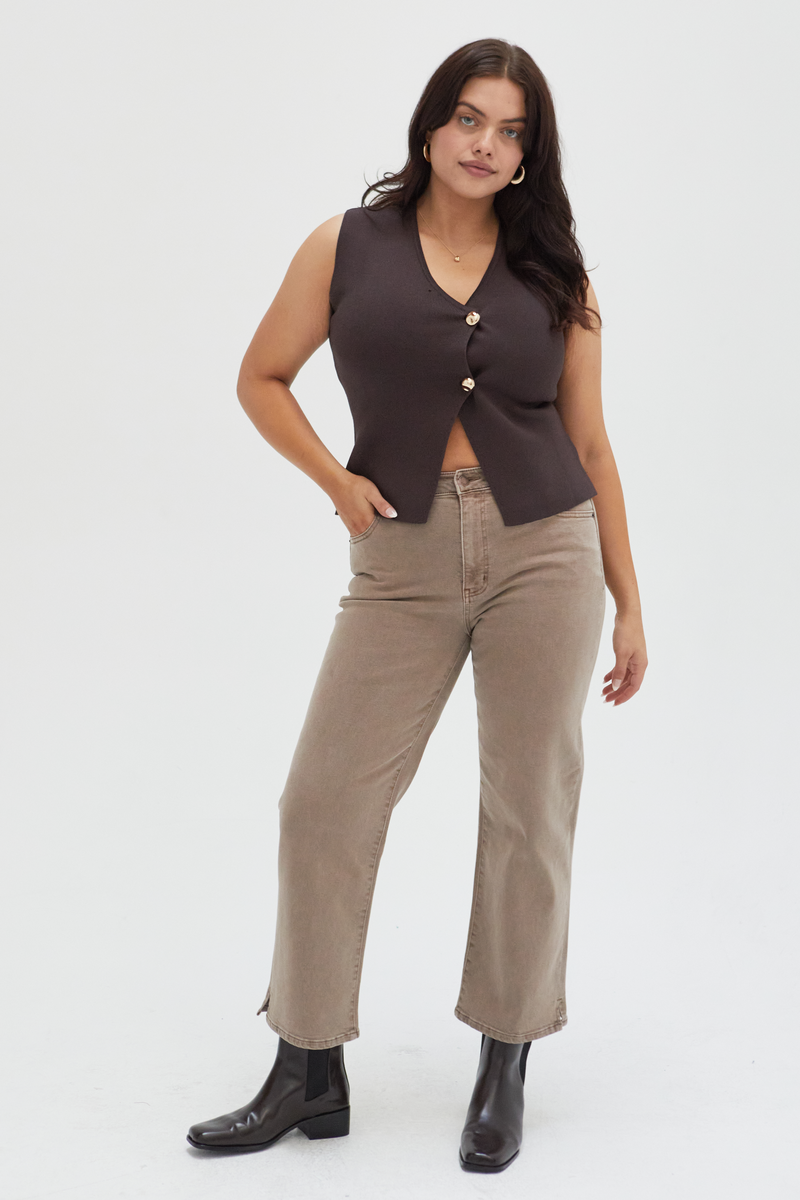 Plus-size model wearing wide-leg ankle crop jeans in a brown wash, styled with a cream ribbed cardigan and black loafers, showcasing a relaxed fit and cropped hem.