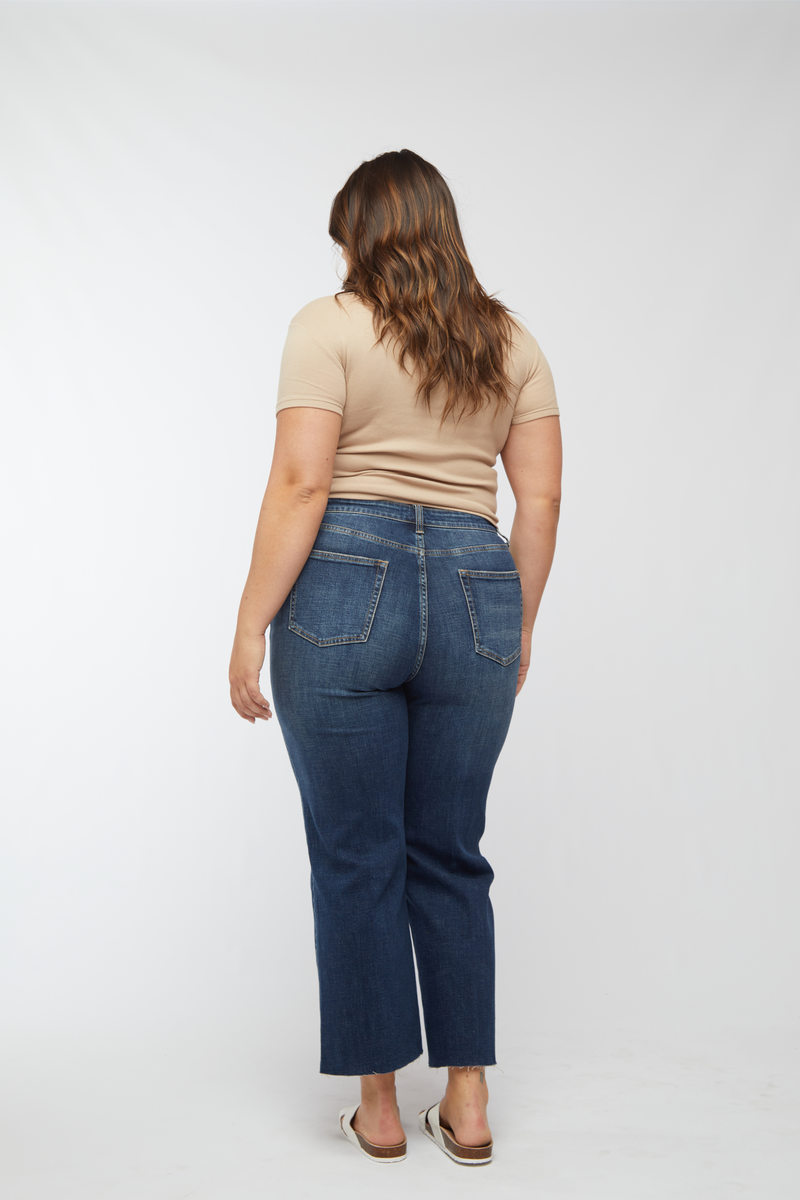 Back view of plus-size model in dark wash wide leg cropped jeans and beige top, showcasing the comfortable fit.