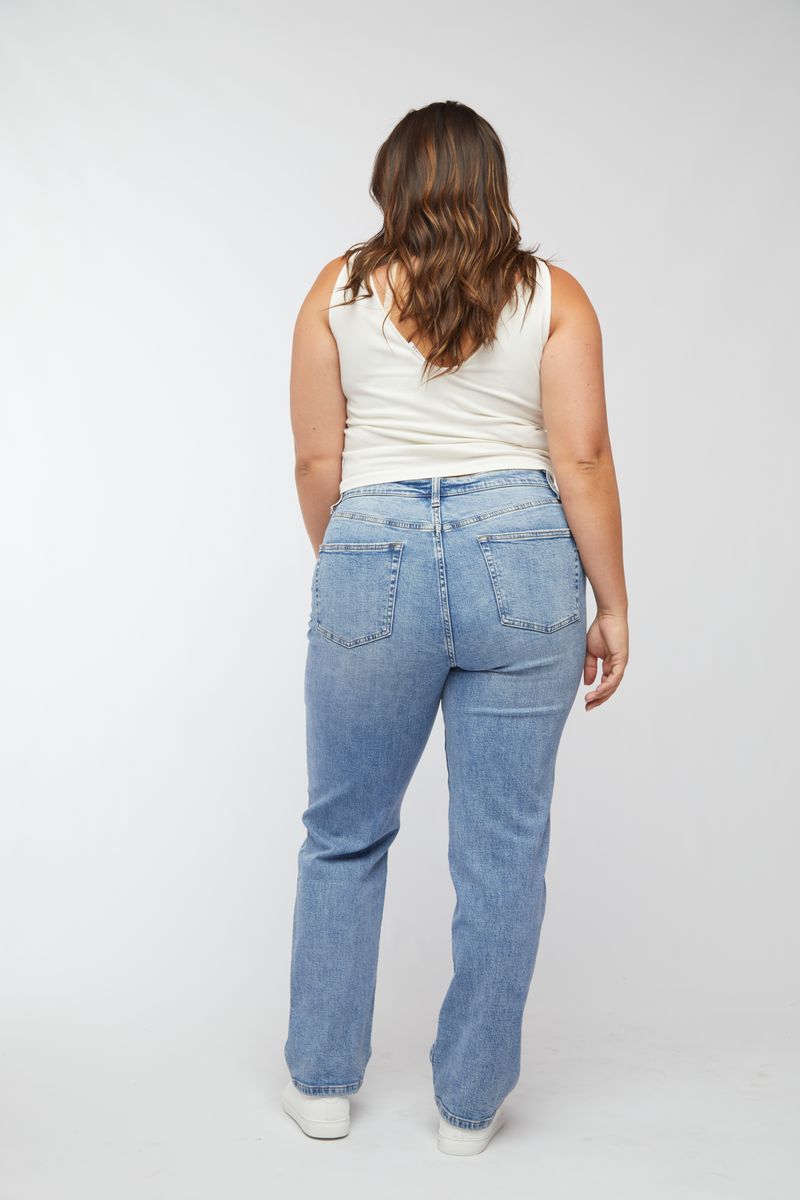 Back view of plus-size model in high rise straight leg jeans, showcasing the light wash and flattering fit.