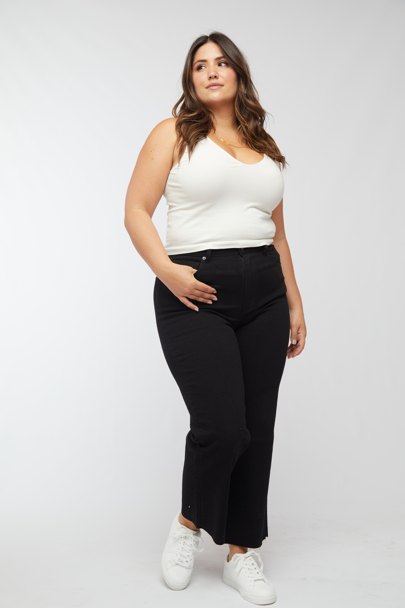 Plus-size model smiling confidently in high waisted black wash wide leg jeans, emphasizing the comfortable and flattering fit.