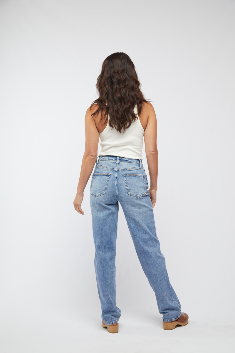 Back view of model wearing light wash high rise straight leg jeans, highlighting the classic blue denim and vintage-inspired fit.