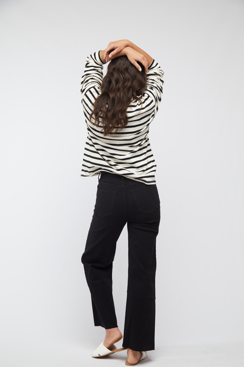 Back view of model in black wash wide leg cropped jeans, styled with white sandals, showcasing the relaxed silhouette.