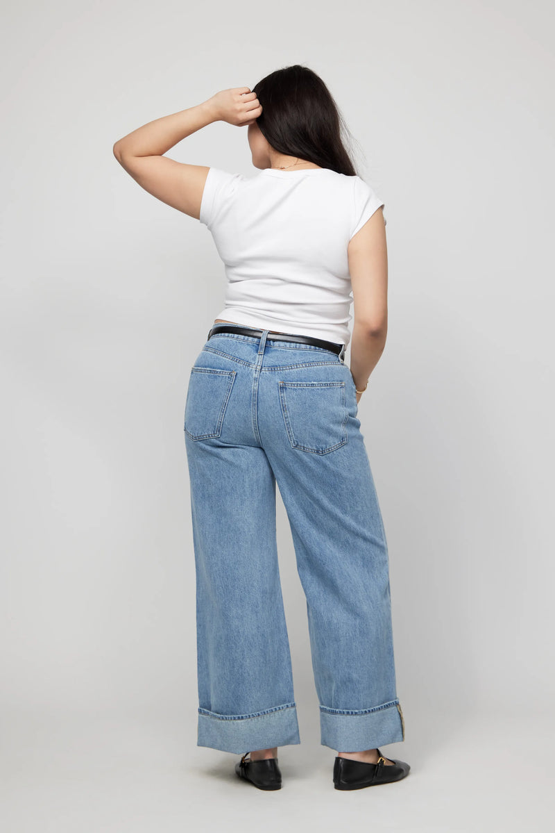 Back view of plus-size mid-rise cuffed wide-leg jeans styled casually in a light blue wash.