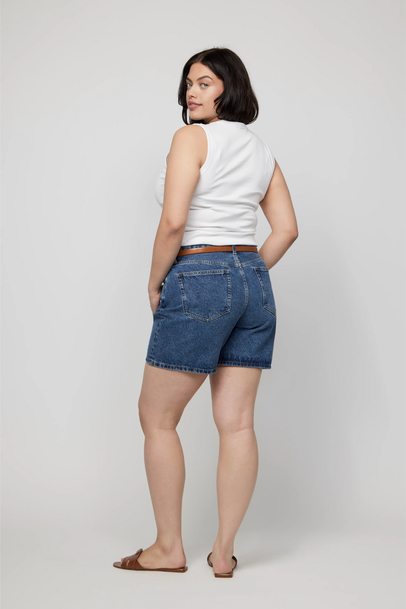 Back view of plus-size high-rise denim shorts styled with a tucked-in tank and summer sandals.