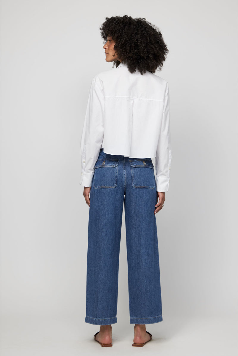 Back view of high-rise wide-leg cropped denim pants in medium indigo wash styled with sandals.