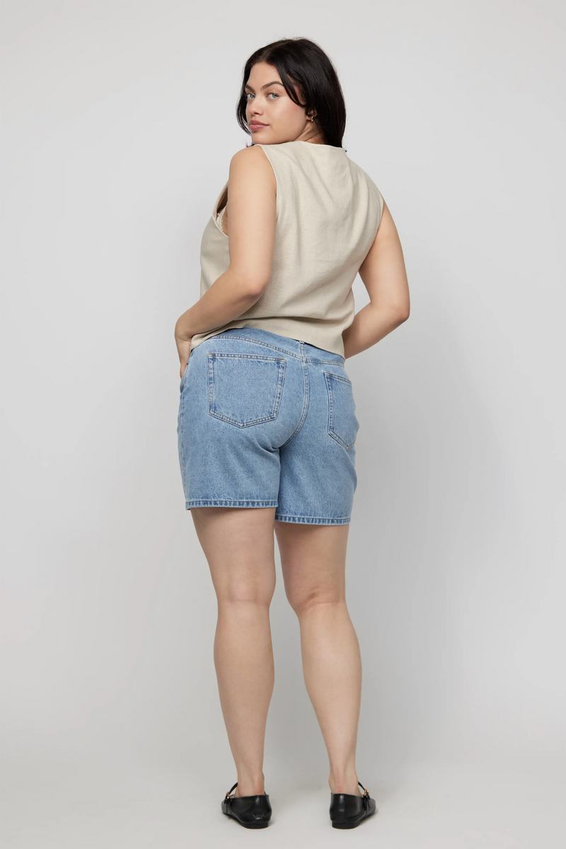 Back view of plus-size model wearing light wash high-rise jean shorts styled for summer.