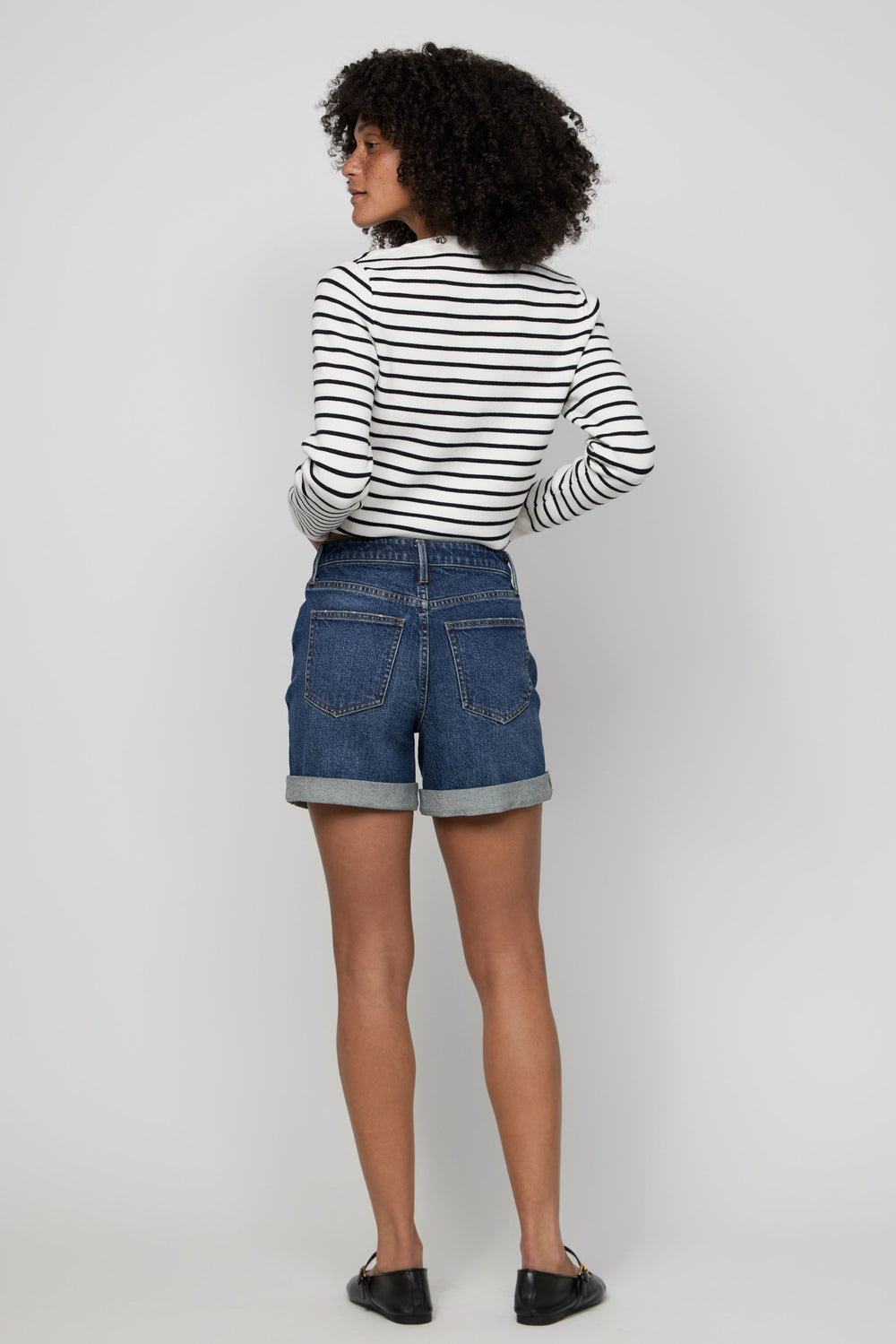 Rear view of high-rise women’s denim shorts in dark wash with rolled cuffs and classic pockets.