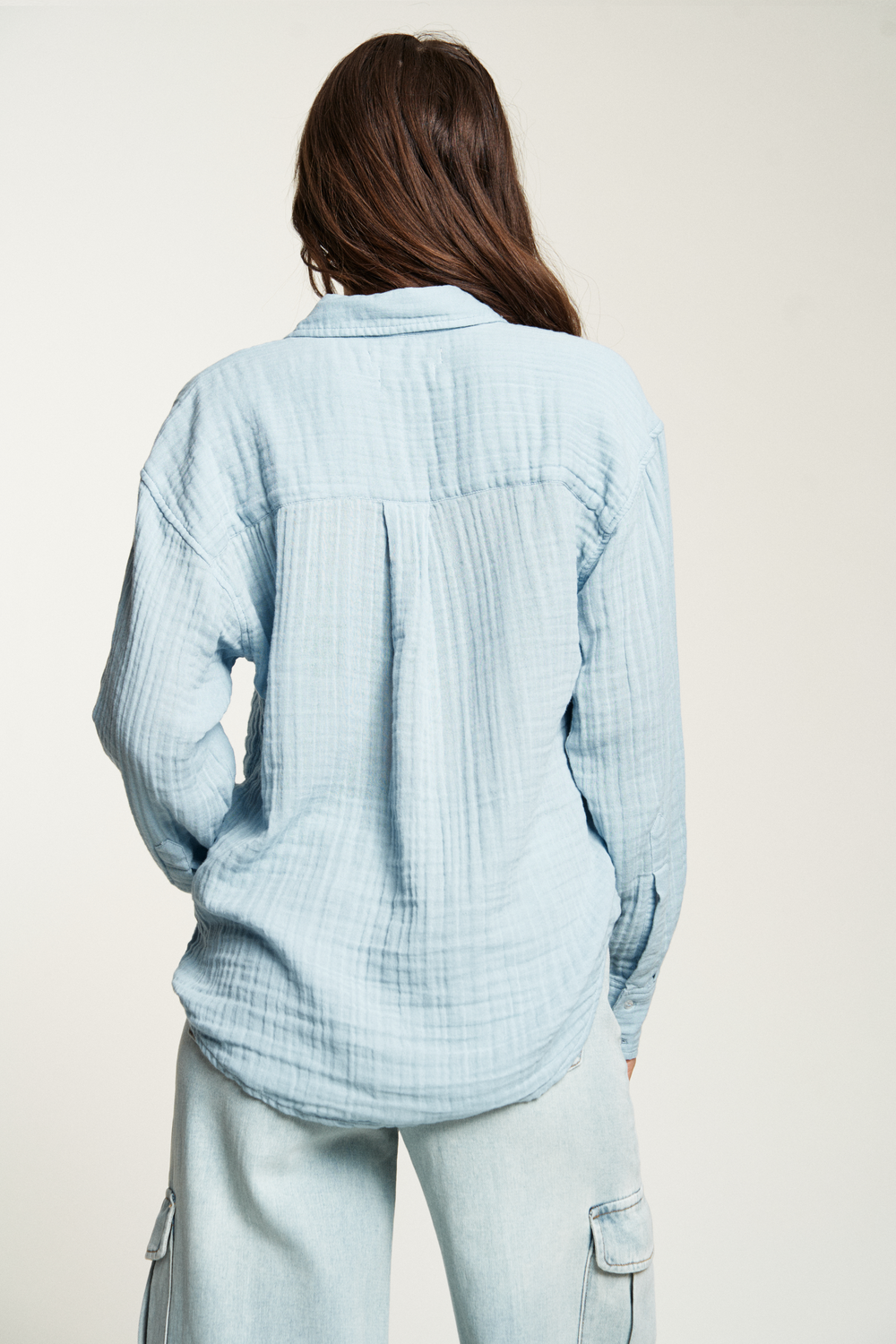 Oversized blue button-up top with a loose, comfortable fit, paired with dark-wash denim for effortless style.