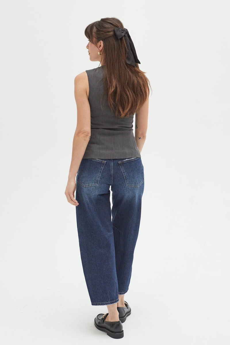 Back view of a model in dark indigo high-rise barrel jeans, highlighting the structured fit and unique silhouette.