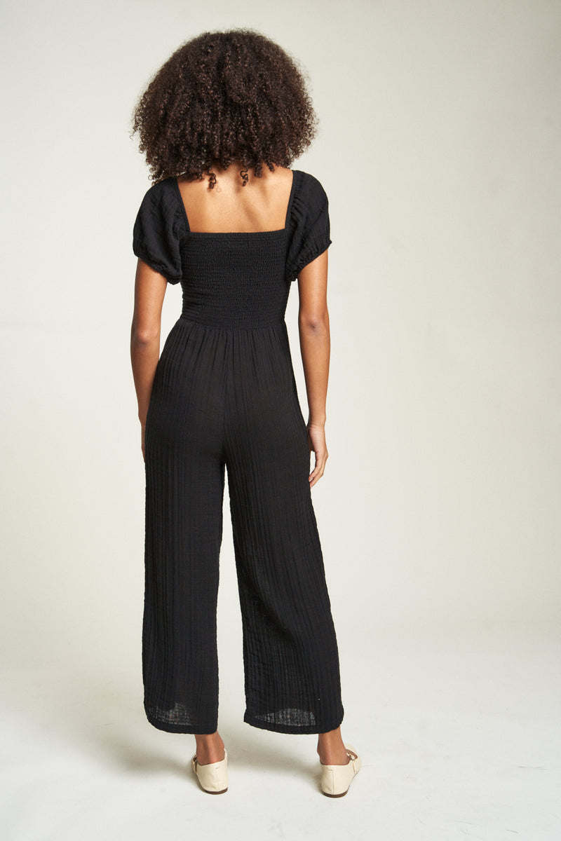 Breathable black romper, made from 100% cotton, offers a comfortable loose fit ideal for casual wear in warm weather.