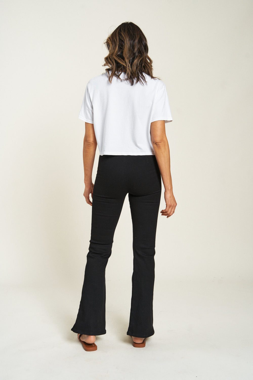 Flare pull-on pants in black, model facing backward, highlighting comfortable fit and wide leg style.