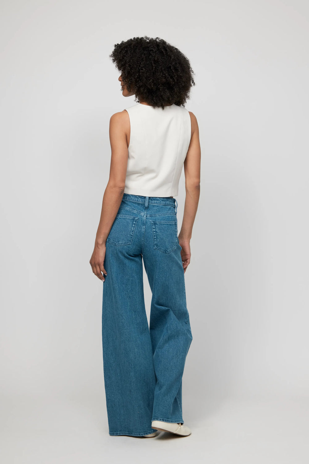 Back view of high-rise wide-leg jeans in medium vintage wash, highlighting relaxed structure and flattering fit.