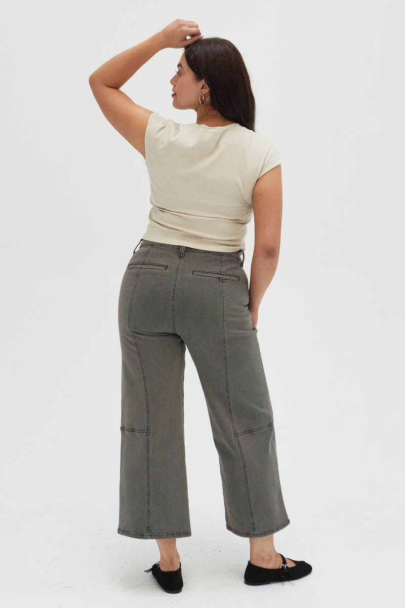 Back view of a plus-size model in olive wide-leg ankle crop jeans, highlighting the unique panel stitching and comfortable fit.