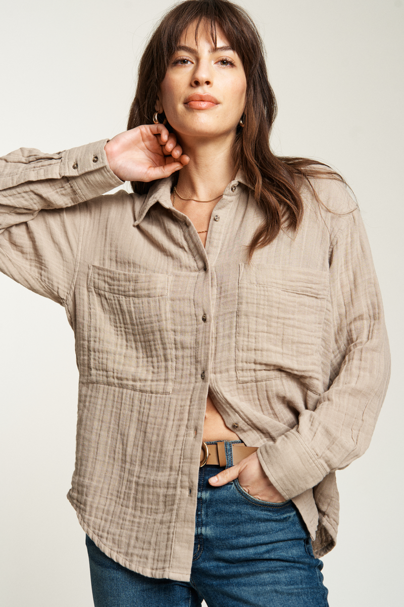 Oversized beige button-up top with a loose, comfortable fit, paired with dark-wash denim for effortless style.