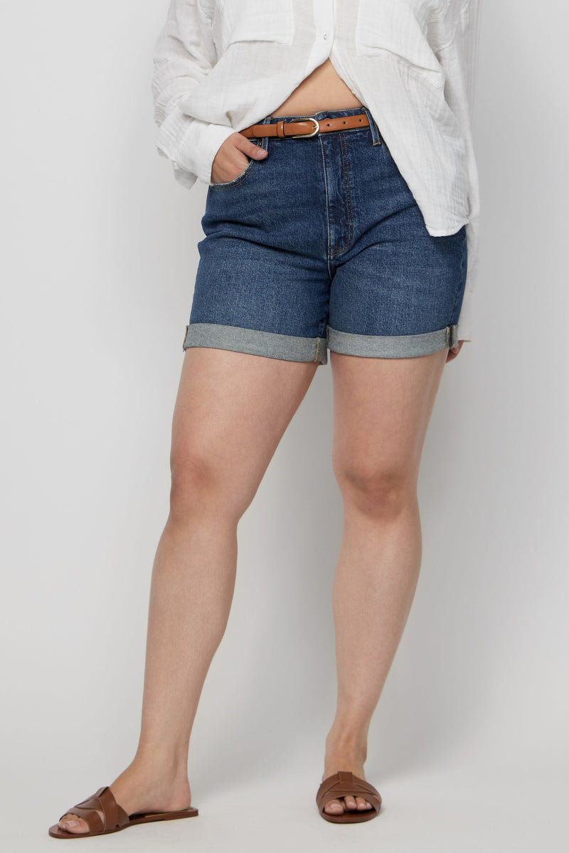 Close-up of high-rise denim shorts for women on a plus-size model, highlighting the flattering fit and dark wash.