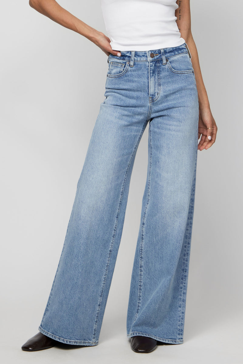 Close-up of light-wash high-rise wide-leg jeans with a slim waist and softly draped leg.