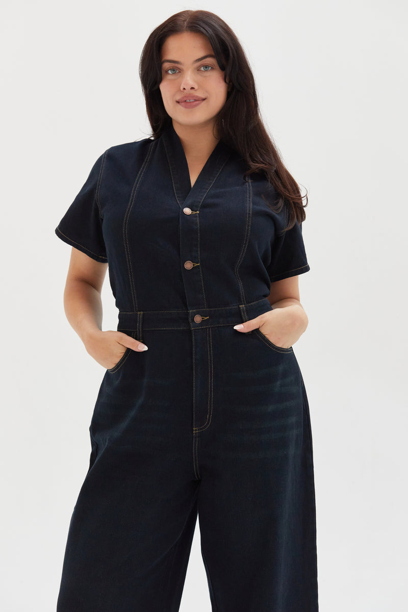 Close-up of the dark indigo denim romper, emphasizing the button-front closure, stitched detailing, and durable fabric.