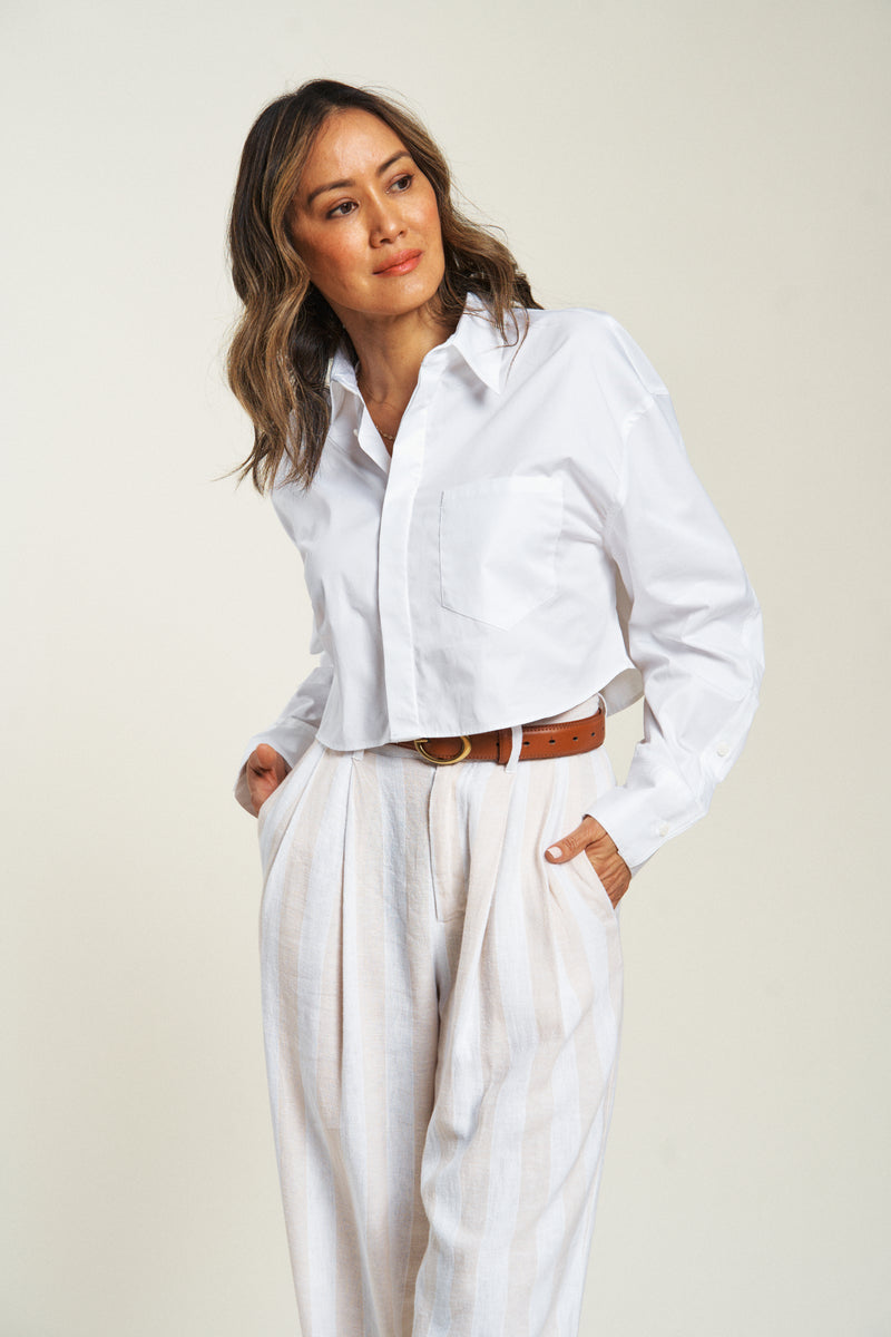 Close-up of lightweight high-waisted dress pants with side pockets, worn with a white shirt and belt for a polished look.
