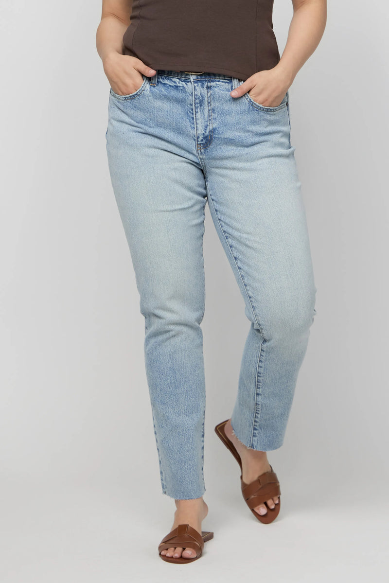 Close-up of plus-size high-rise light wash denim jeans with subtle fading and relaxed straight leg fit.