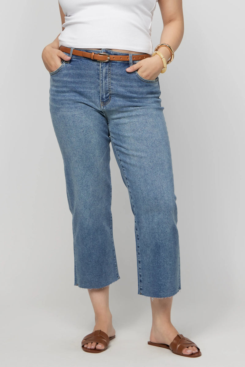 Close-up of plus-size high-rise cropped jeans with a brown belt, showcasing waist-defining fit and comfort-stretch denim.