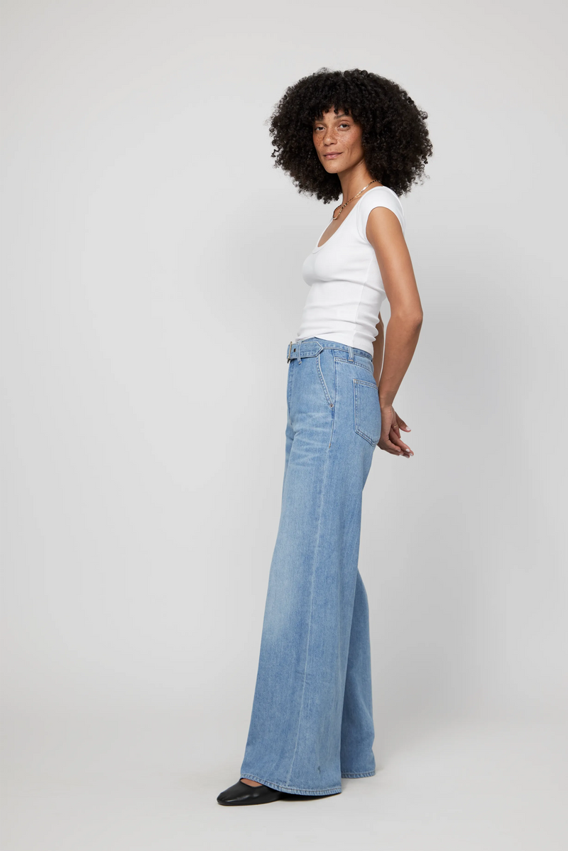 Side view of high-rise wide-leg denim jeans for women, styled with a tucked-in tank and minimal accessories.