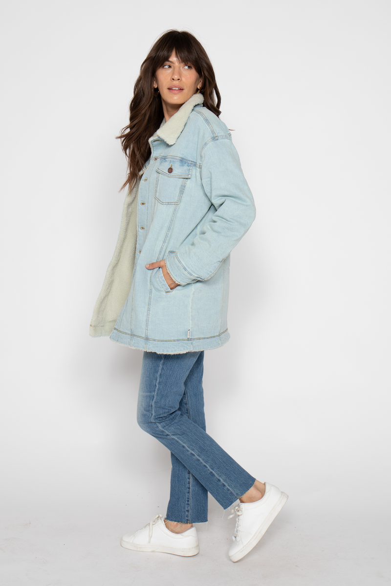 Side view of the model posing in the coat, showing the relaxed fit and casual style of the outfit.