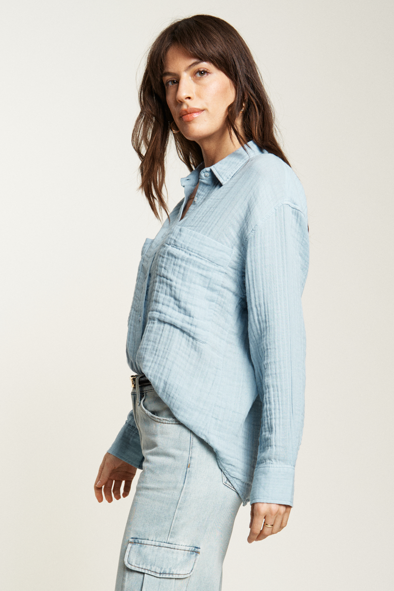 Lightweight blue button-up top featuring large front pockets and a relaxed silhouette, ideal for casual, laid-back outfits.