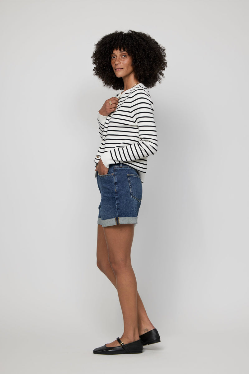 Side angle showing the relaxed fit and structure of high-rise rolled cuff denim shorts in a dark wash.
