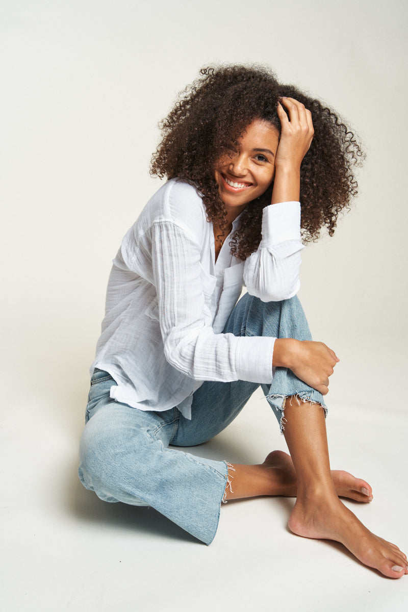 Women’s white button-up top designed with long sleeves and breathable fabric.