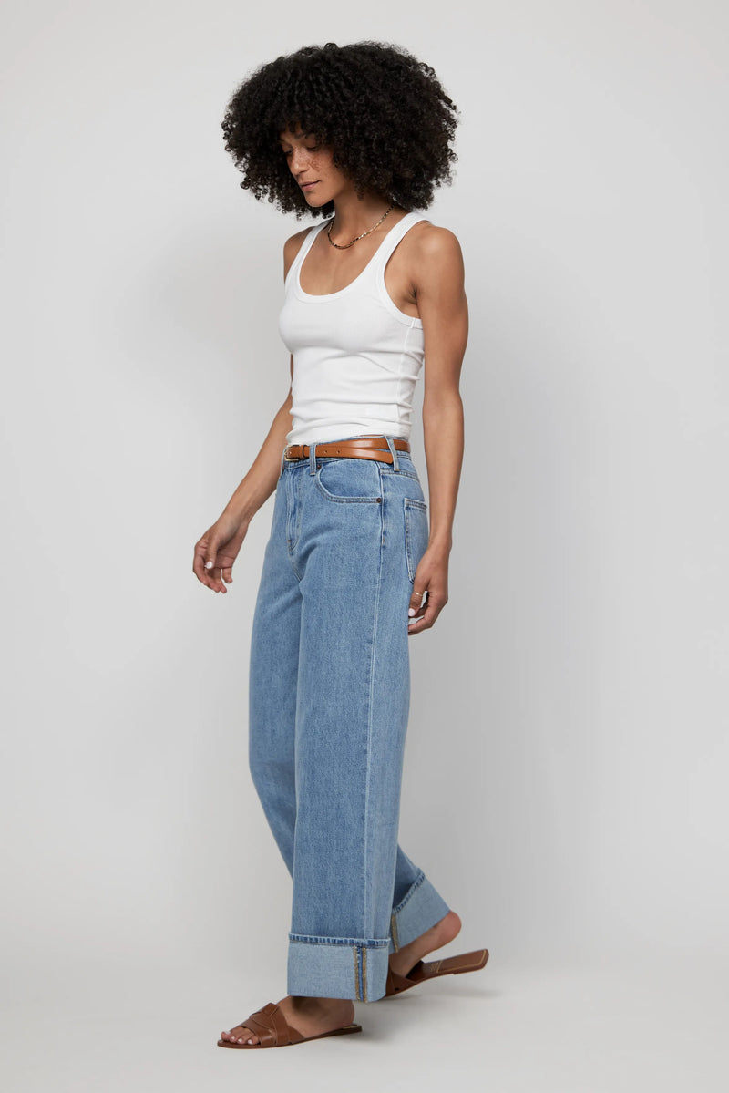 Angled pose of mid-rise light wash wide-leg jeans with turned-up cuffs styled casually.