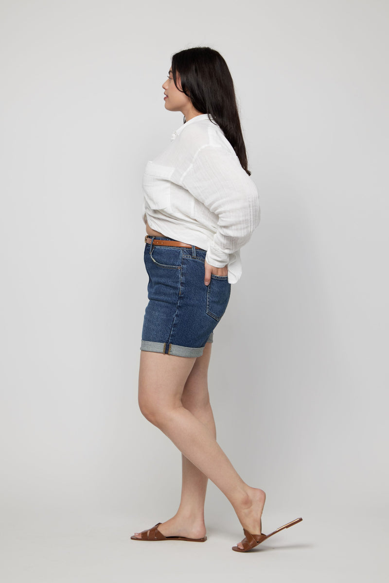 Video of a plus-size woman wearing high-rise denim shorts for women in a dark indigo wash.