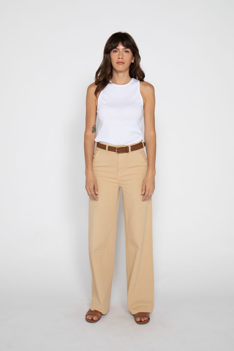 Model styling beige high-waisted wide-leg pants with a white tank, side view.