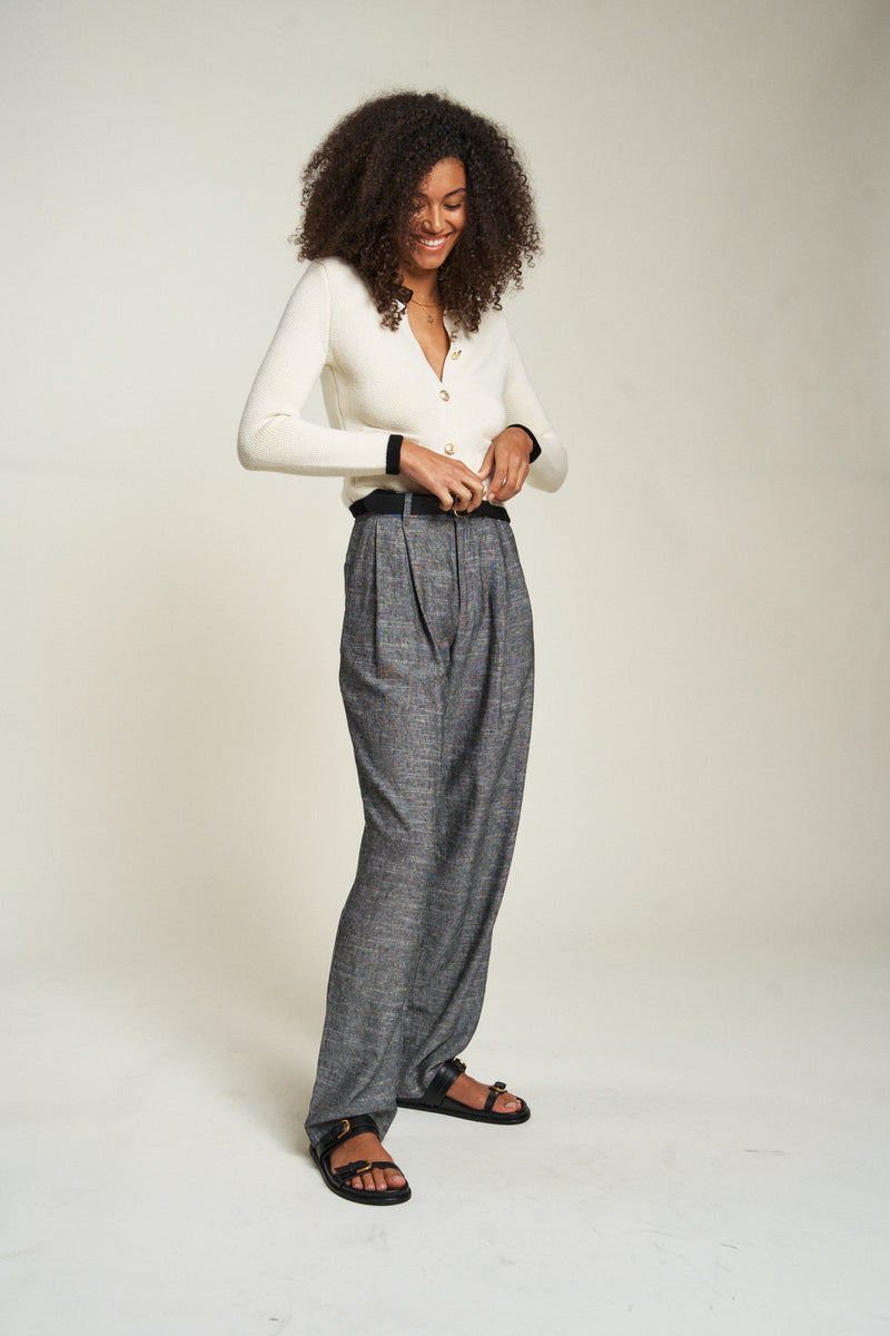 Side view of the pleated trousers with a tucked-in blouse, highlighting the lightweight fabric. These 100% cotton pants are perfect for warmer weather.