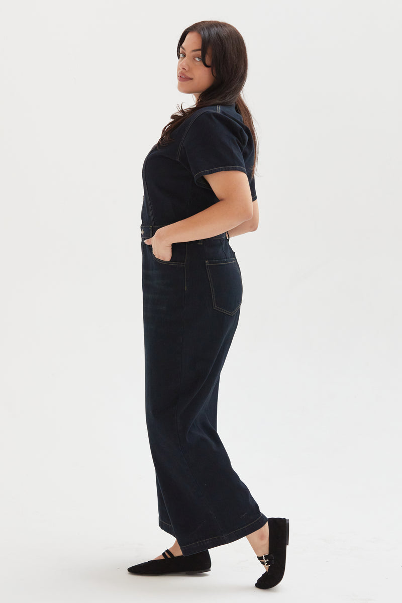 Side view of a plus-size model in a denim romper, showcasing the flattering fit and modern silhouette.