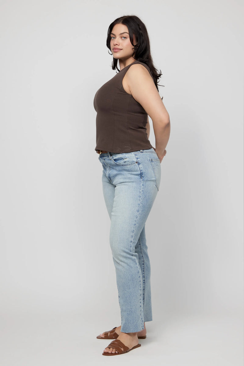 Side profile of plus-size model in high-rise relaxed light wash jeans and brown slide sandals.