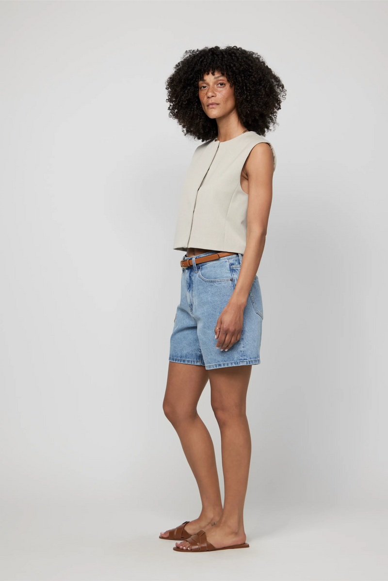 Side view of light blue high-rise denim shorts on woman wearing a cropped neutral tank.