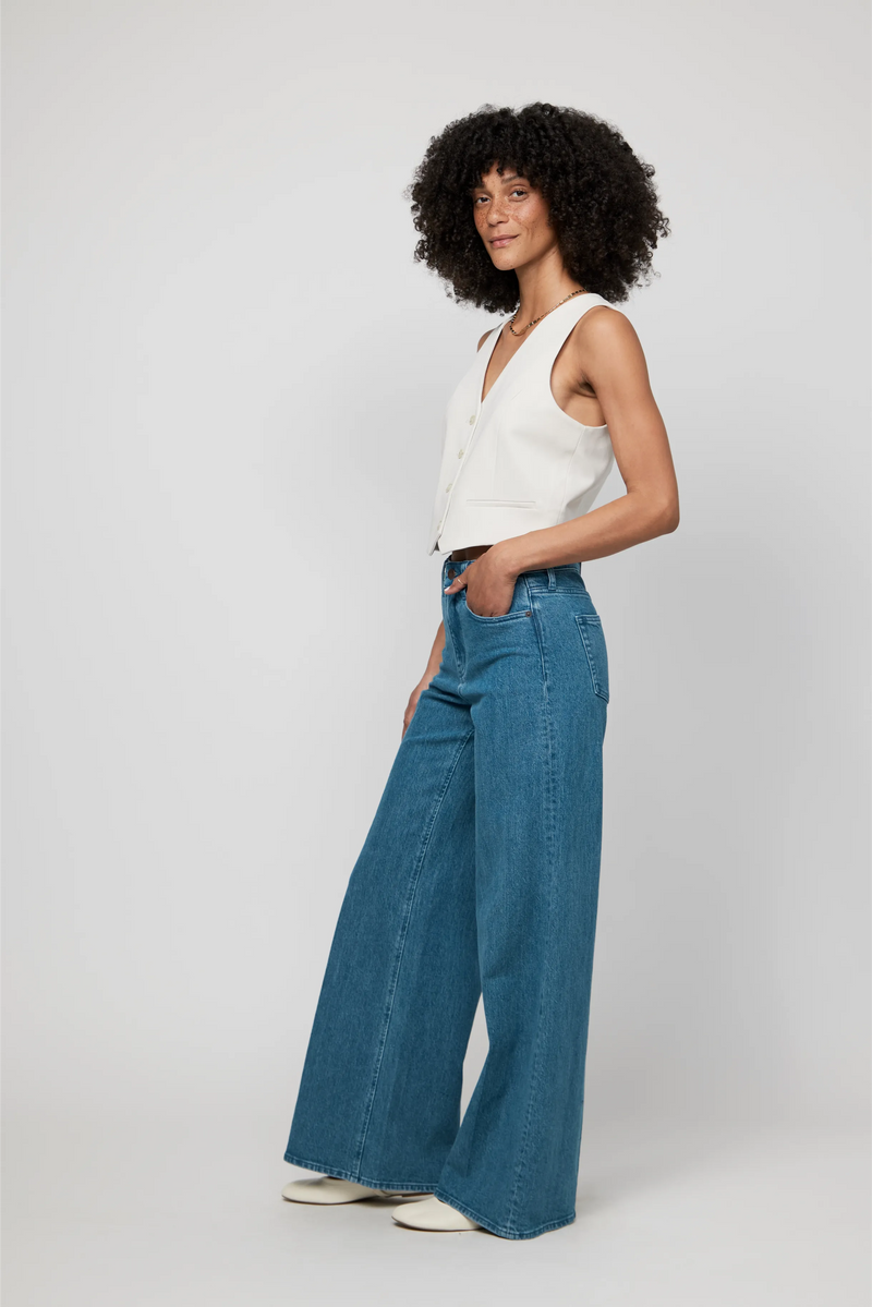 Side angle of high-rise wide-leg jeans in medium blue denim, styled with white sneakers for a casual, modern feel.