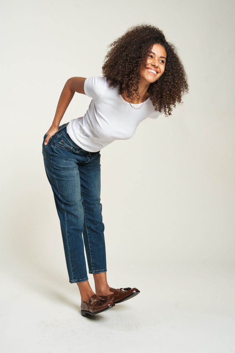 Side view of the model wearing straight legged jeans in dark-wash denim. The vintage look offers a timeless and versatile appeal.