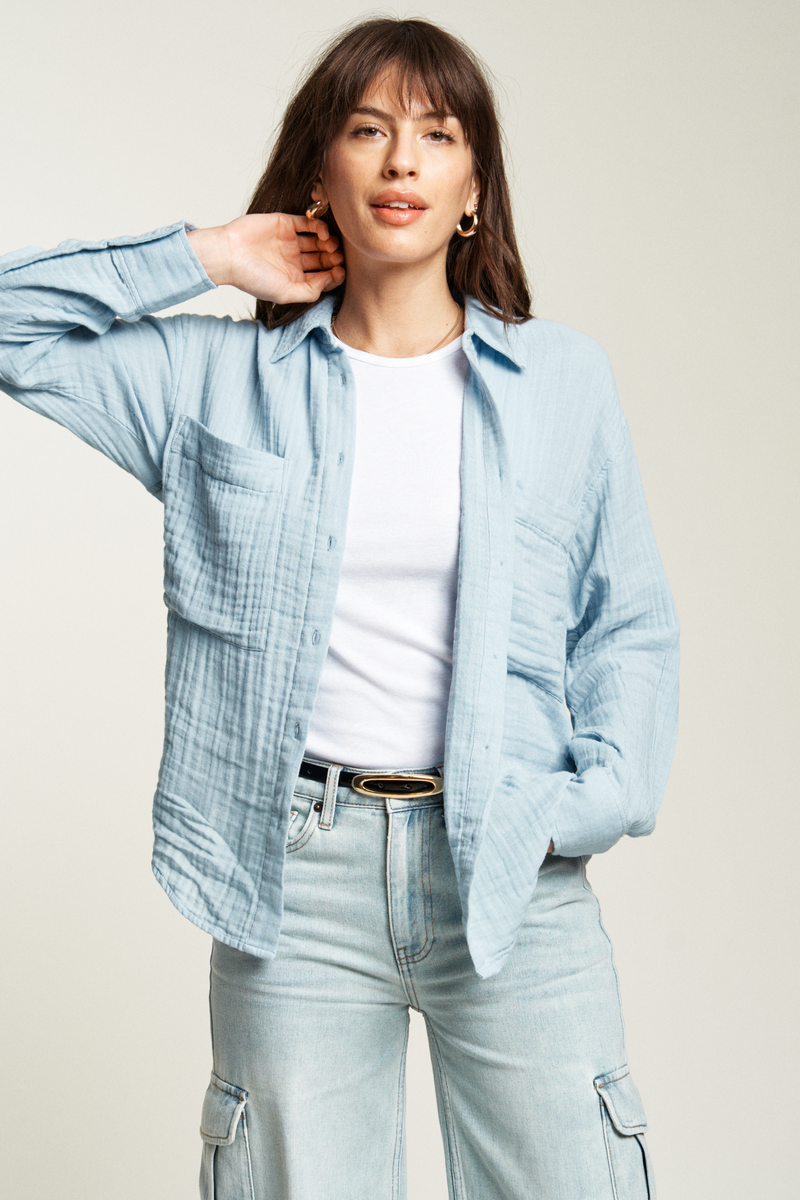 Blue button-up shirt styled with a belt and mid-rise jeans, offering a chic, easy-to-wear look for casual days.