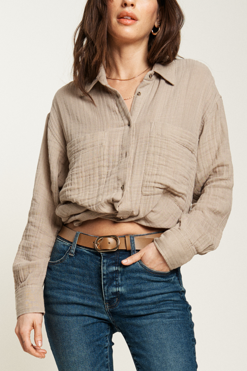 Beige button-up shirt styled with a belt and mid-rise jeans, offering a chic, easy-to-wear look for casual days.