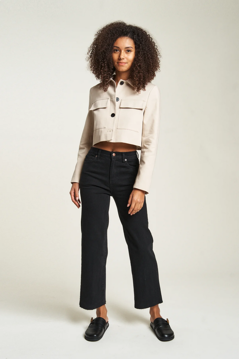 Model wearing black wash cropped wide leg jeans with a beige cropped jacket, front view showing the sleek fit