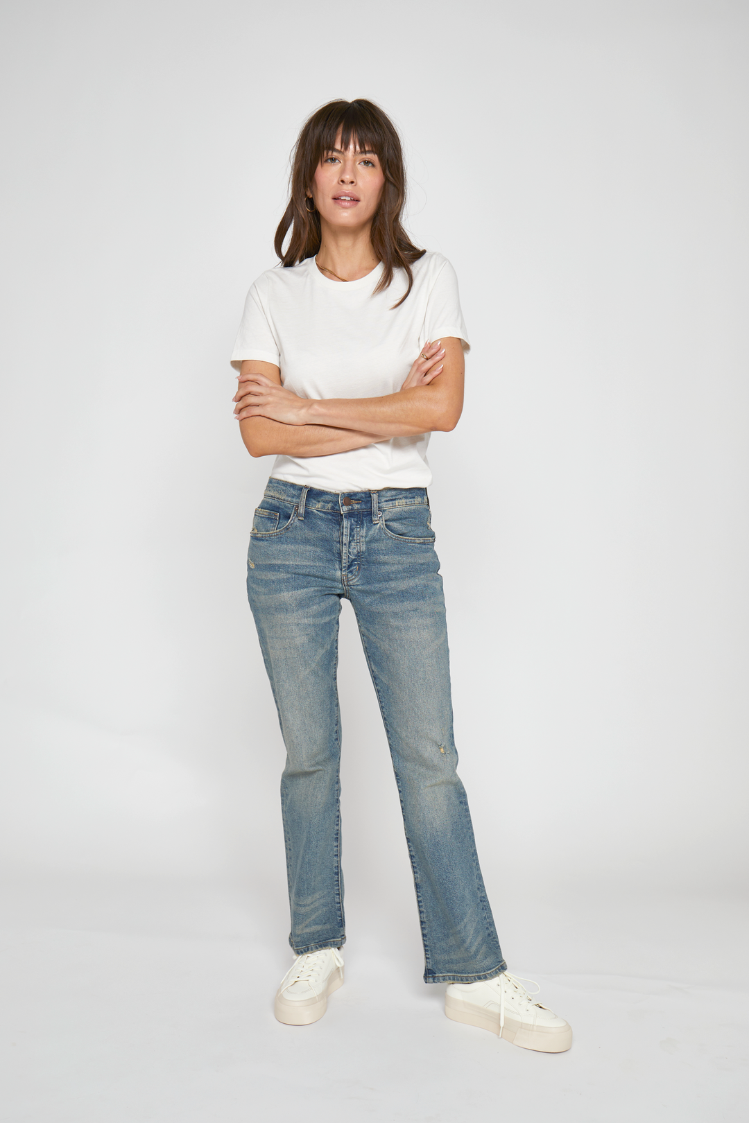 Model in front view wearing vintage wash mid-rise straight-leg jeans paired with a white t-shirt and sneakers.