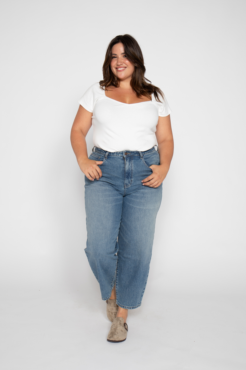 Front view of plus-size model wearing high rise barrel leg jeans, styled with a white tee, highlighting the wide leg crop style.