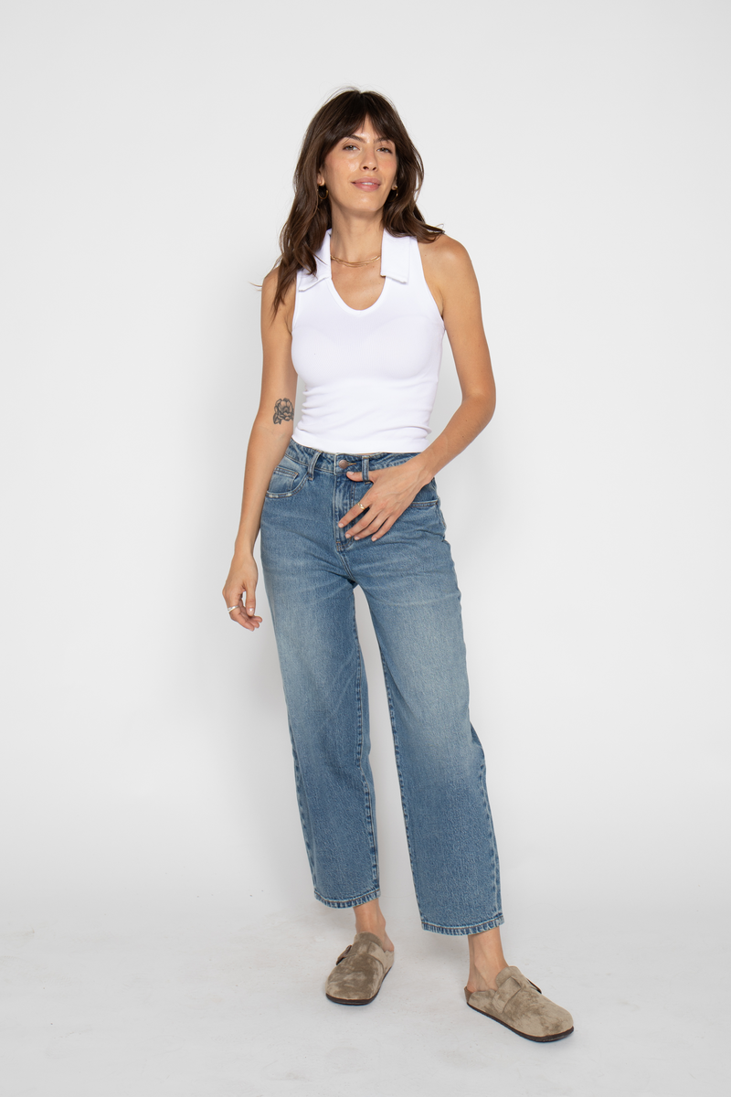 Front view of model wearing high waisted wide leg cropped jeans, styled with a white tank top, highlighting barrel leg denim.